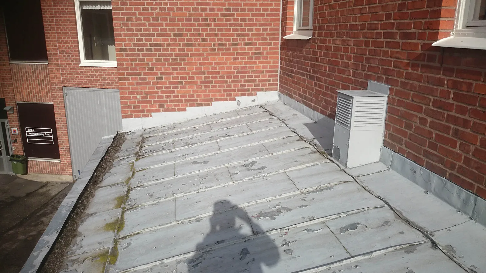 Slitet, lappat tak med nötta plattor och mossa före renovering