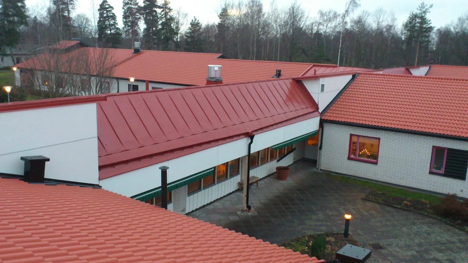Rött falsat plåttak i skymning på offentlig byggnad